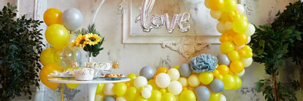 Photo zone for a photo session. Yellow and gray balloons are collected in an arch. Aero design and candy bar with sweets for a festive event.